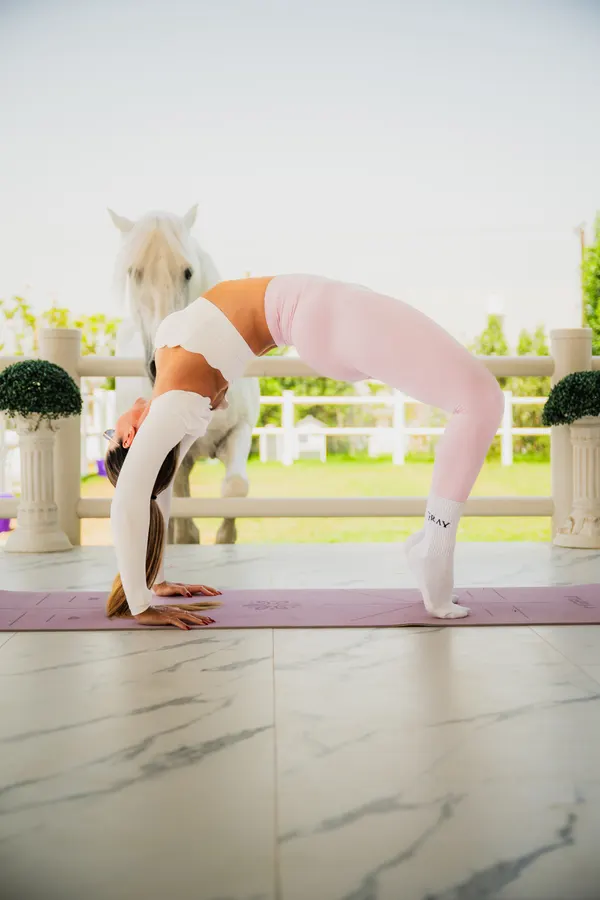 Yoga backbend on platform with white horse at Crystalline Equine